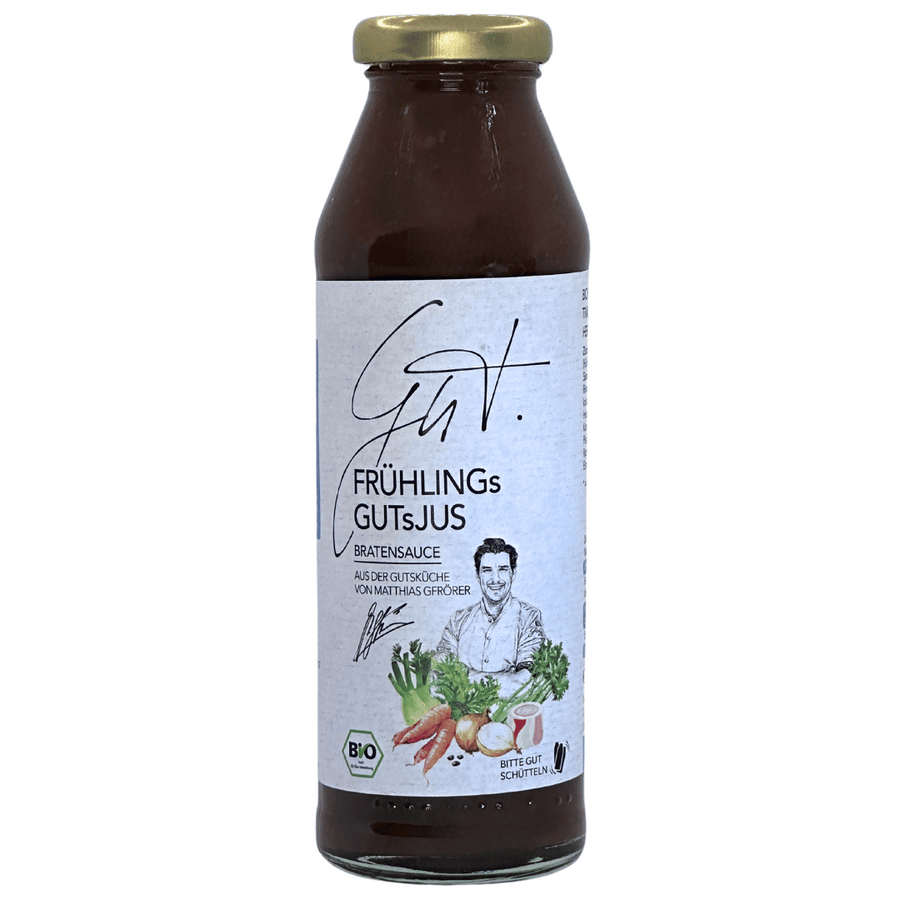Eine Flasche Matthias Gfrörers Bio Frühlings GUTsJUS, ein Bio-Saft auf Gemüsebasis, mit einem Etikett mit Bildern von frischem Gemüse und zwei Köchen. Das Produkt ist als bio und glutenfrei gekennzeichnet.