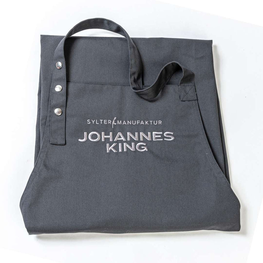 Graue Stofftasche mit Aufdruck „Sylter Manufaktur Johannes King“ auf der Vorderseite, nachhaltig produziert, auf weißem Hintergrund.