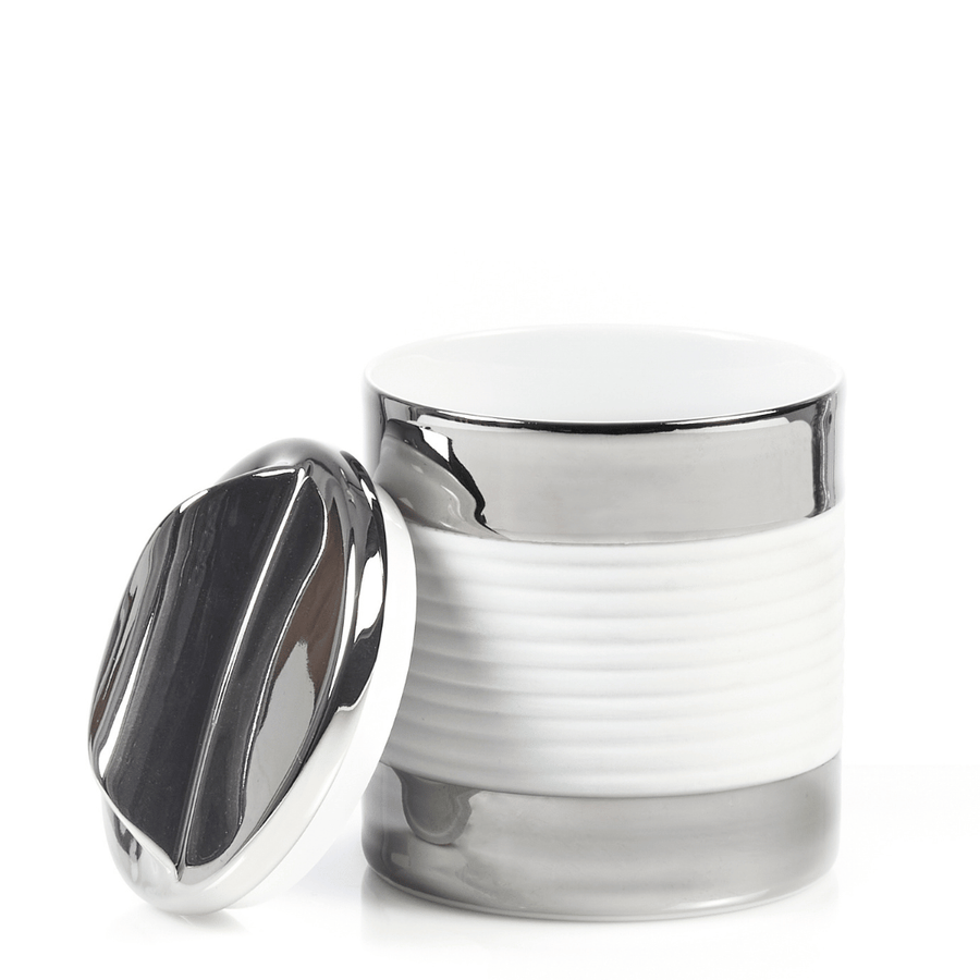 Eine Suppendose aus Porzellan der Sylter Manufaktur mit seitlich platziertem, reflektierendem Metalldeckel auf weißem Hintergrund.
