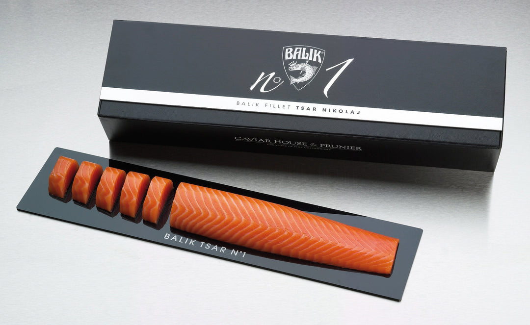 Eine Verpackung mit der Aufschrift "Balik Filet Tsar Nikolaj N° 1 *Black Edition*" von Dieckmann & Hansen enthält ein längliches Lachsfilet mit mehreren sauber angeordneten Scheiben auf einem schwarzen Tablett.