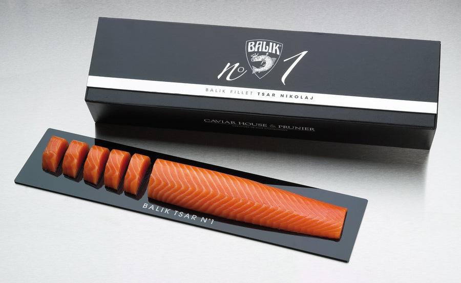 Eine Verpackung mit der Aufschrift "Balik Filet Tsar Nikolaj N° 1 *Black Edition*" von Dieckmann & Hansen enthält ein längliches Lachsfilet mit mehreren sauber angeordneten Scheiben auf einem schwarzen Tablett.