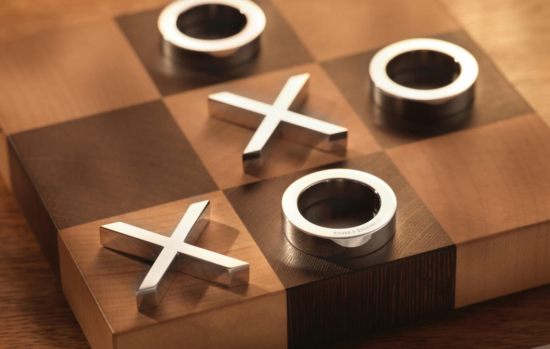 Nahaufnahme Tic Tac Toe aus Silber, polierte Kreuze und Ringe auf dem Holzbrett aus Ahorn und Wengé