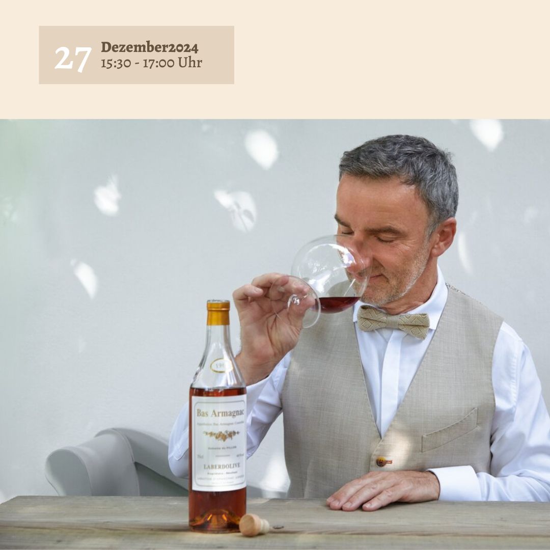 Ein Mann in beiger Weste und Fliege riecht an einem Glas braunen Schnaps. Vor ihm steht auf einem Holztisch eine Flasche Sylter Manufaktur Johannes King Bas Armagnac samt Korken. Im Hintergrund steht „Armagnac Tasting – 27. Dezember 2024, 15:30 - 17:00 Uhr“.