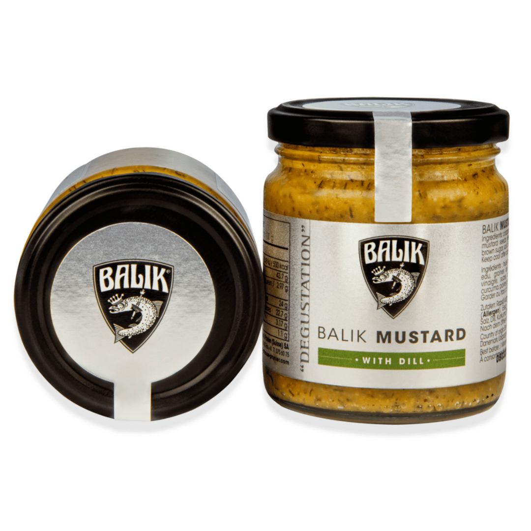 Ein Glas Balik Senf-Dill-Sauce vom Kaviarhaus Prunier neben seinem Deckel auf weißem Hintergrund.