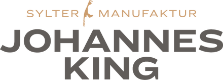 Das Bild zeigt das Logo für „Johannes King Sylter Manufaktur“, das wie ein Markenname aussieht, mit stilisiertem Text und einem grafischen Element, das an einen tropfenden Löffel oder eine Inselsilhouette über dem Buchstaben „i“ in „Sylter“ erinnert.