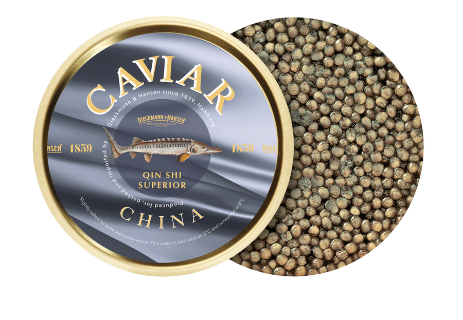 Eine geöffnete runde Dose Dieckmann & Hansen Kaviar Qin Shi Superior gibt den Blick auf hellbraunen Kaviar frei. Der gold- und silberfarbene Deckel zeigt daneben die Produktangaben.