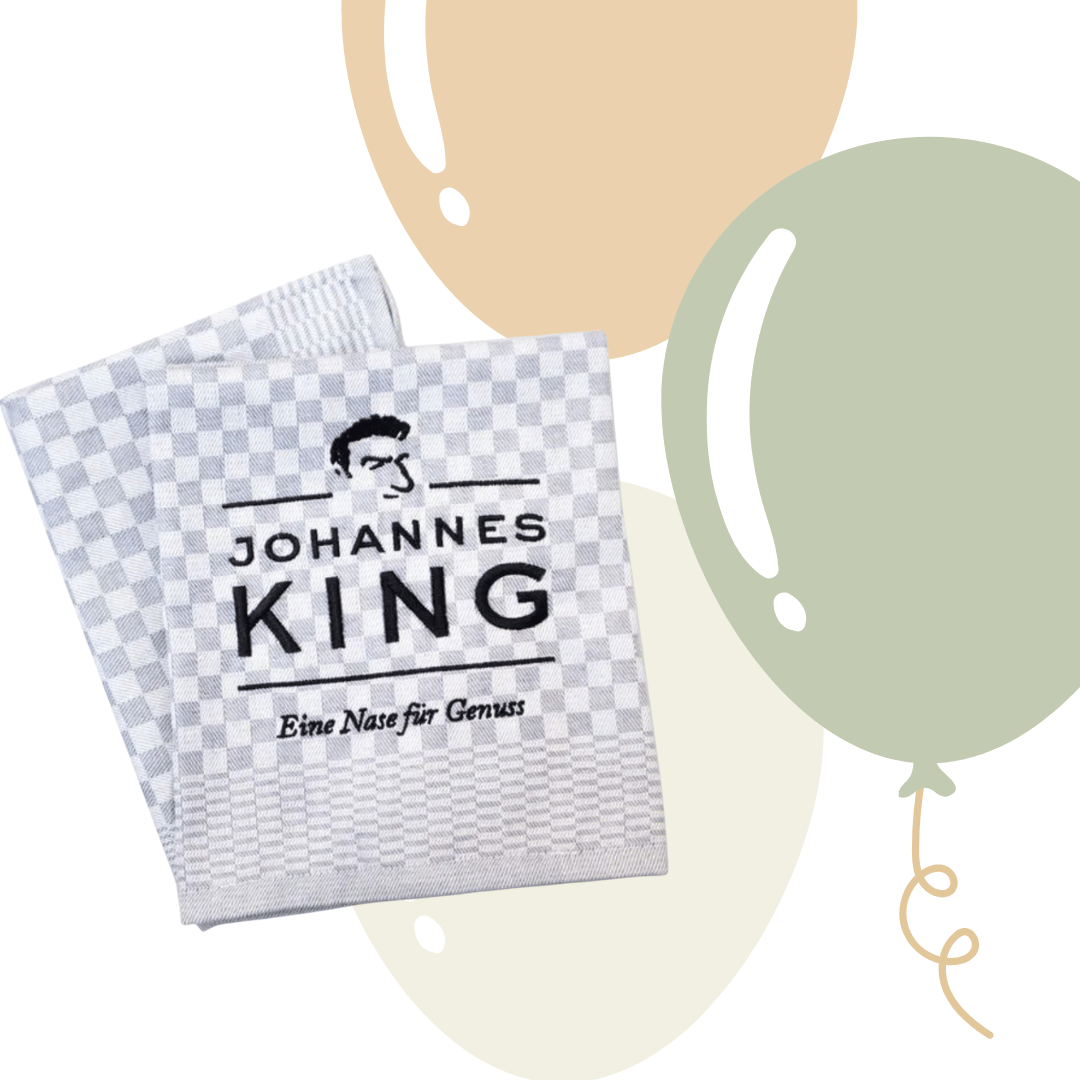 Ein Touchon mit Johannes King-Logo mit schwarz-weißem Schachbrettmuster und dem Logo „Johannes King – eine Nase für Genuss“ überlagert auf einem abstrakten Hintergrund mit kreisförmigen Formen. (Markenname: Sylter Manufaktur)