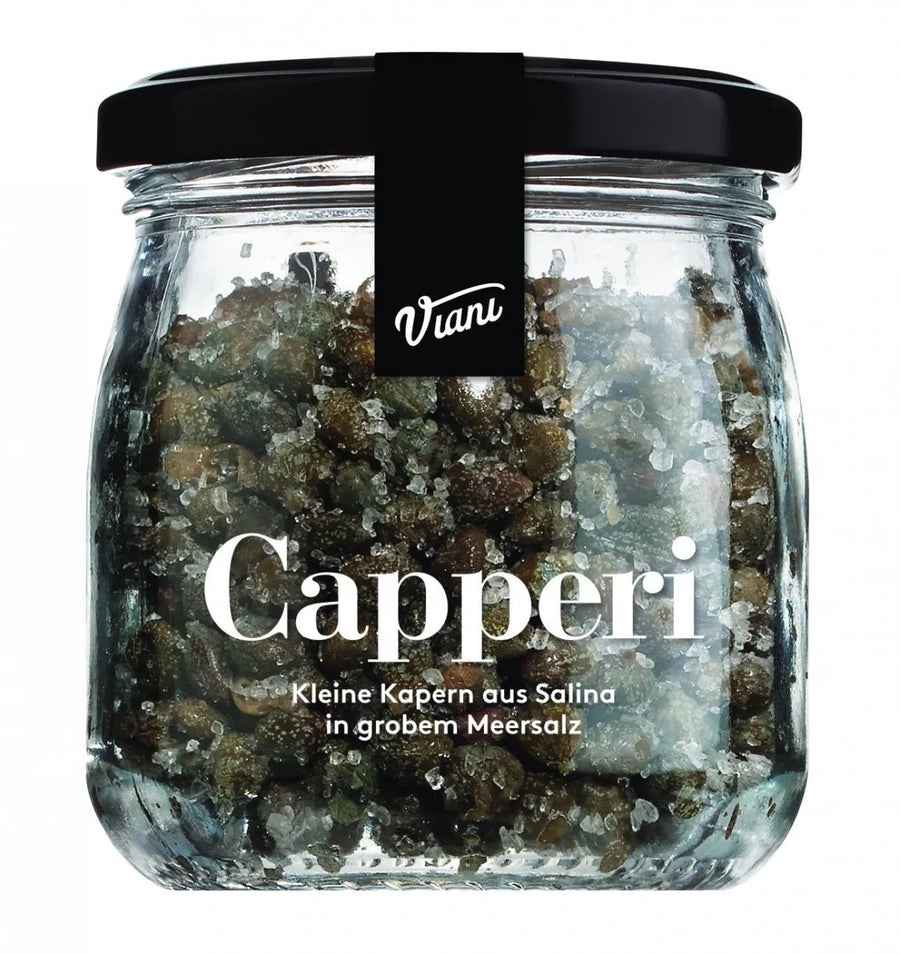 Ein Glas Kleine Kapern der Marke Cascina San Giovanni in Meersalz mit der Aufschrift „Capperi“, was auf kleine Kapern aus Salina hinweist, die in grobem Meersalz eingelegt sind.