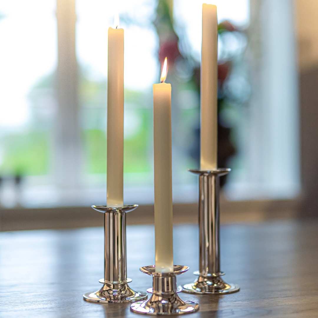 Drei Kerzen in Silberwaren made in Germany Robbe & Berking Kerzenleuchter Alta auf einem Tisch, mit der mittleren Kerze entzündet.