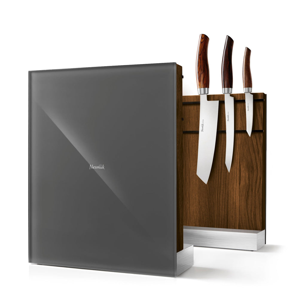 Ein moderner Nesmuk Messerhalter mit einem Satz von vier Messern, mit einer dunkelgrauen, reflektierenden Oberfläche und einem Holzhalter vor einem weißen Hintergrund.