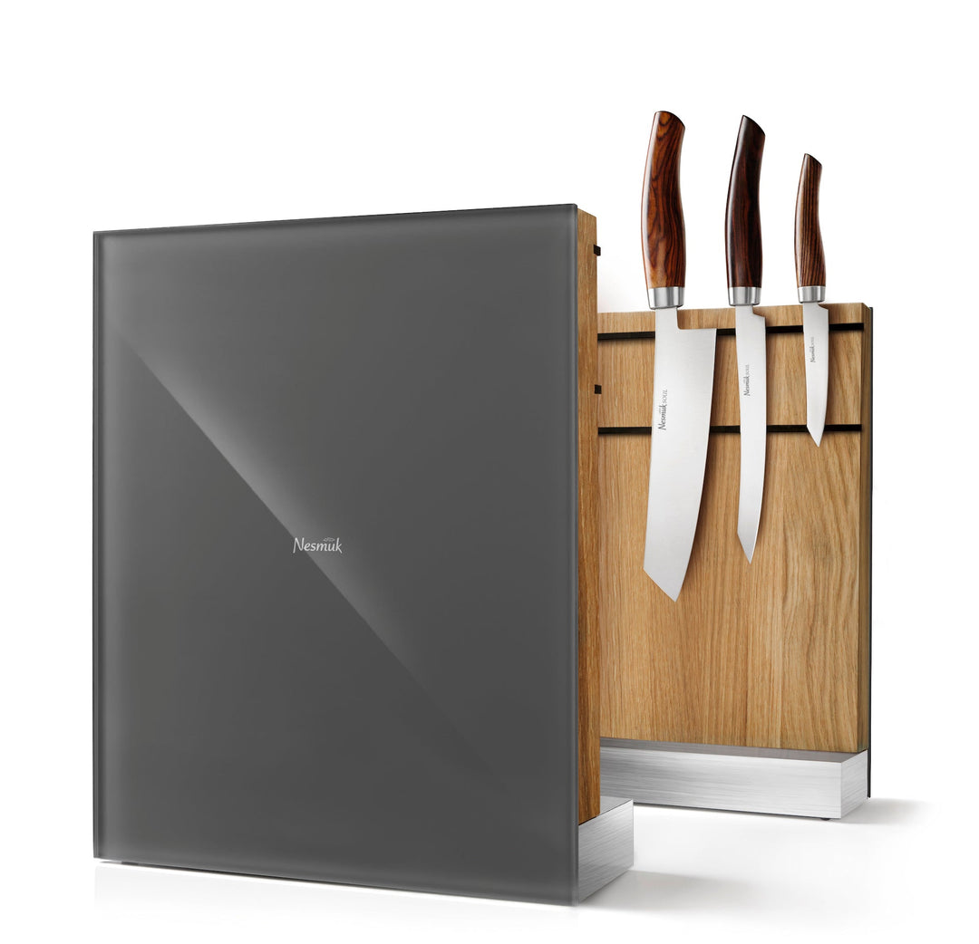 Ein moderner Nesmuk-Messerblock mit einem Satz Messer, einem Holzständer und einem eleganten grauen, schildartigen Hintergrund aus Gummileder.