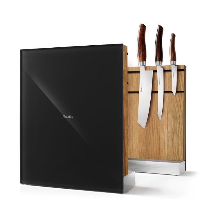 Ein moderner Nesmuk-Messerhalter mit einem Satz von vier Nesmuk-Messern, ausgestattet mit einem Holzhalter und einer schwarzen, reflektierenden Oberfläche aus Gummileder auf einer Seite.