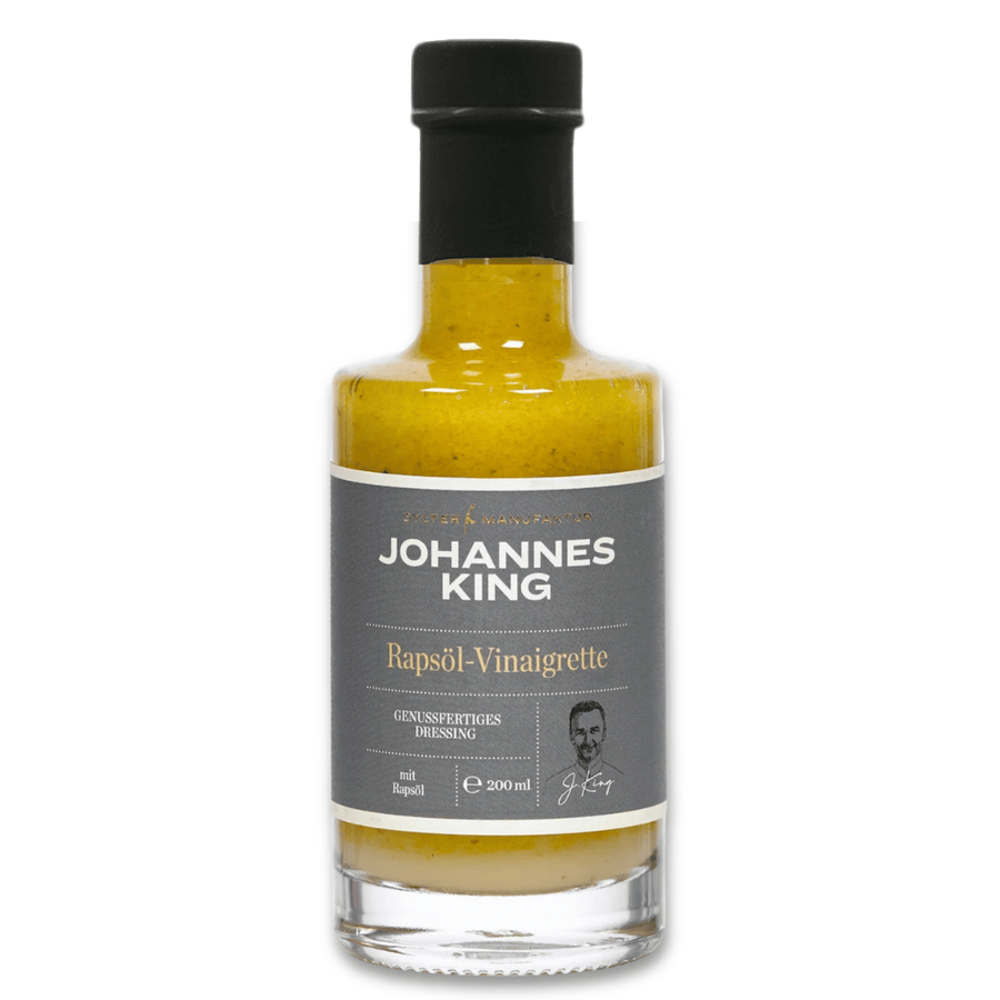 Eine Flasche Sylter Manufaktur Johannes King Rapsöl-Vinaigrette mit einem schwarz-weißen Etikett mit der Silhouette eines Kochs.
