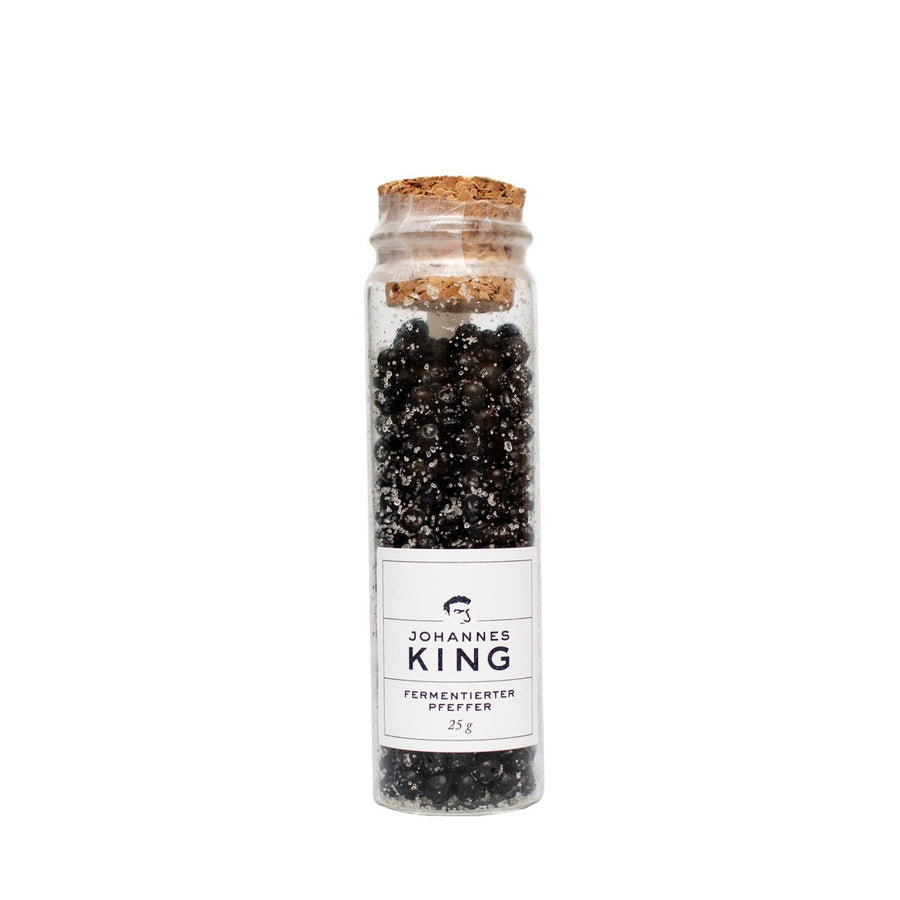 Ein mit schwarzen Pfefferkörnern gefülltes Glas, mit einem Korken verschlossen und mit der Aufschrift „Sylter Manufaktur Kings Fermentierter Pfeffer im Reagenzglas 25g“ versehen.