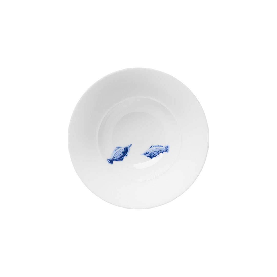 Ein weißer Teller von Hering Berlin mit zwei blauen Fischmotiven auf der Oberfläche, isoliert auf weißem Hintergrund.