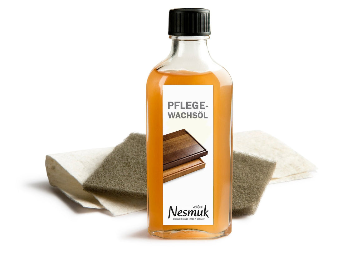 Eine Flasche Nesmuk Accessoires Pflegewachsöl mit Schwamm und Holzprobe auf weißem Untergrund, ideal zum Ölen von Holzschneidebrettern.