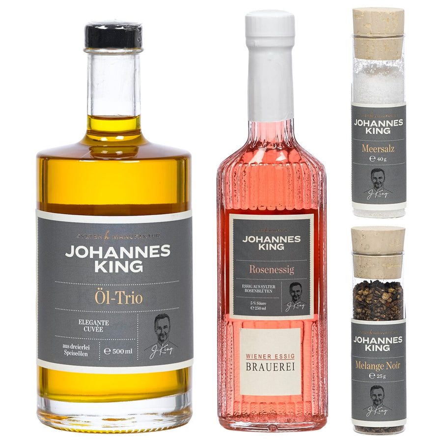 Drei Flaschen Kulinarik-Produkte der Marke Sylter Manufaktur Johannes King, darunter eine Flasche Öl-Trio, eine Flasche Rosen-Vinaigrette-Set und eine Mühle mit schwarzer Gewürzmischung.
