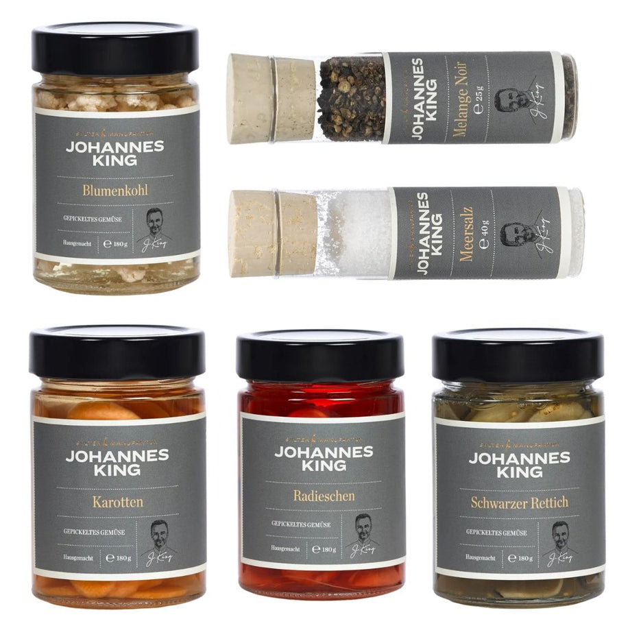 Eine Sammlung von sechs Gourmet-Lebensmitteln mit der Bezeichnung „Sylter Manufaktur“, darunter konservierter Blumenkohl, eine Gewürzmischung namens Mélange Noir Pfeffer und Meersalz namens Sylter Meersal.