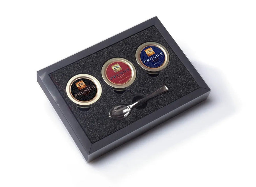 Ein Caviar House Prunier Kaviar-Probierset mit drei kleinen Gläsern Kaviar und einem Perlmuttlöffel, präsentiert in einer schwarzen Box mit Schaumstoffeinlage.
