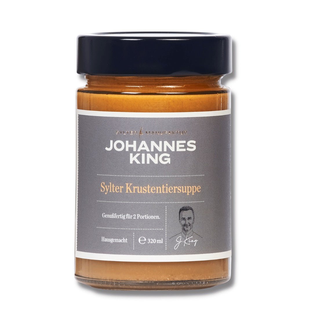 Ein 320 ml Glas „Sylter Krustentiersuppe“ von Sylter Manufaktur Johannes King, eine klassische Küstenküchensuppe. Das Etikett suggeriert, dass es für zwei Portionen reicht und zeigt ein graues Design mit dem Markennamen und einem kleinen Bild eines Mannes in der Ecke.