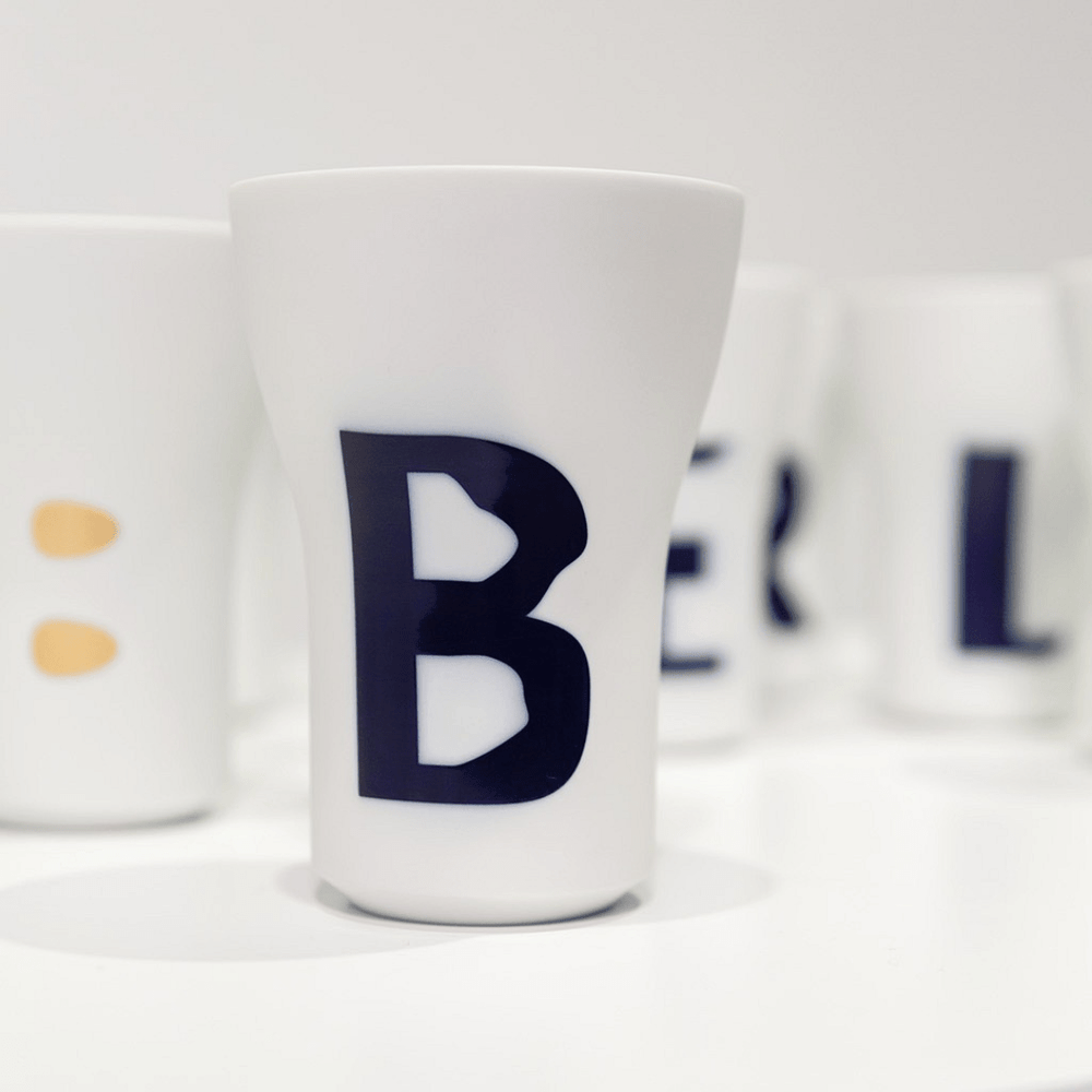 Hering Berlin Becher, groß Buchstabenbecher mit einzelnen Buchstaben darauf, wobei der Buchstabe „b“ deutlich auf dem nächsten Becher abgebildet ist.