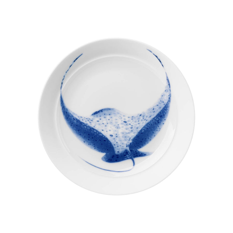Ein weißer Porzellanteller mit einem blau-weißen Design und einem illustrierten Walschwanz in der Mitte, der Hering Berlin flacher Teller, hoher Rand Ocean Rochen Teller.