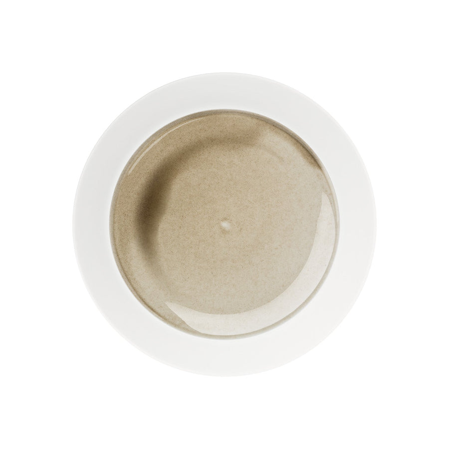 Draufsicht auf eine Schüssel cremige Suppe in einem Hering Berlin flacher Teller, hoher Rand Silent Brass auf weißem Hintergrund.