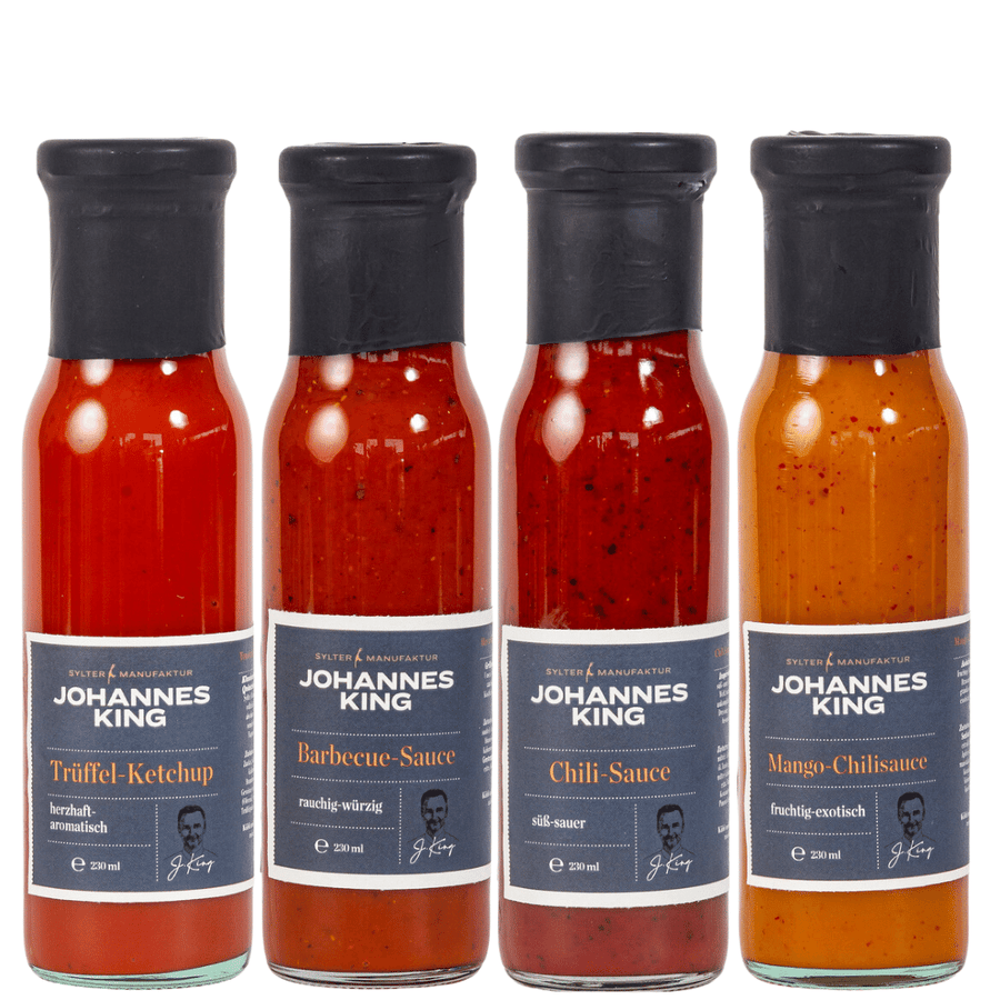 Vier Flaschen Sylter Manufaktur-Saucen, darunter Trüffel-Ketchup, Barbecue-Sauce, Chili-Sauce und Mango-Chili-Sauce, in einer Reihe angeordnet als Teil des Sylter Grillsaucen-Sets.