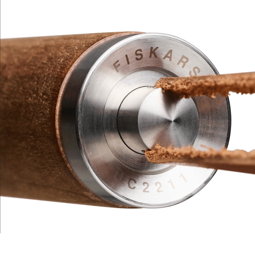 Eine Nahaufnahme eines Holzbleistifts, der mit einem Bleistiftspitzer der Marke Fiskars gespitzt wird. Dieser hat Edelstahlkomponenten und enthält ein Grillwerkzeug-Set für Feinschmecker der Sylter Manufaktur.
