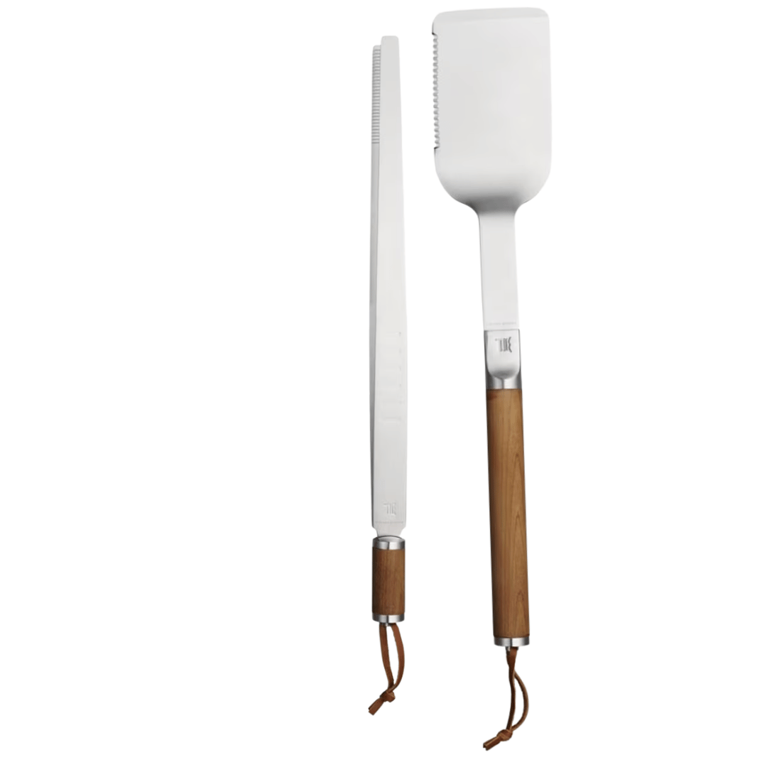 Zwei Grillutensilien – ein langes Messer und ein Pfannenwender mit Holzgriffen und Metallschlaufen zum Aufhängen – stehen isoliert auf weißem Hintergrund als Teil eines Sylter Steak-Sets der Sylter Manufaktur.