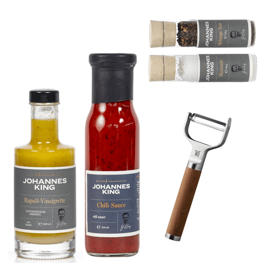 Eine Sammlung von Gourmet-Kondimenten und einem Sylter Manufaktur Gourmet-Set für Salatfans, einschließlich einer Flasche Rapsöl-Vinaigrette, einem Fiskars Profi-Sparschäler.