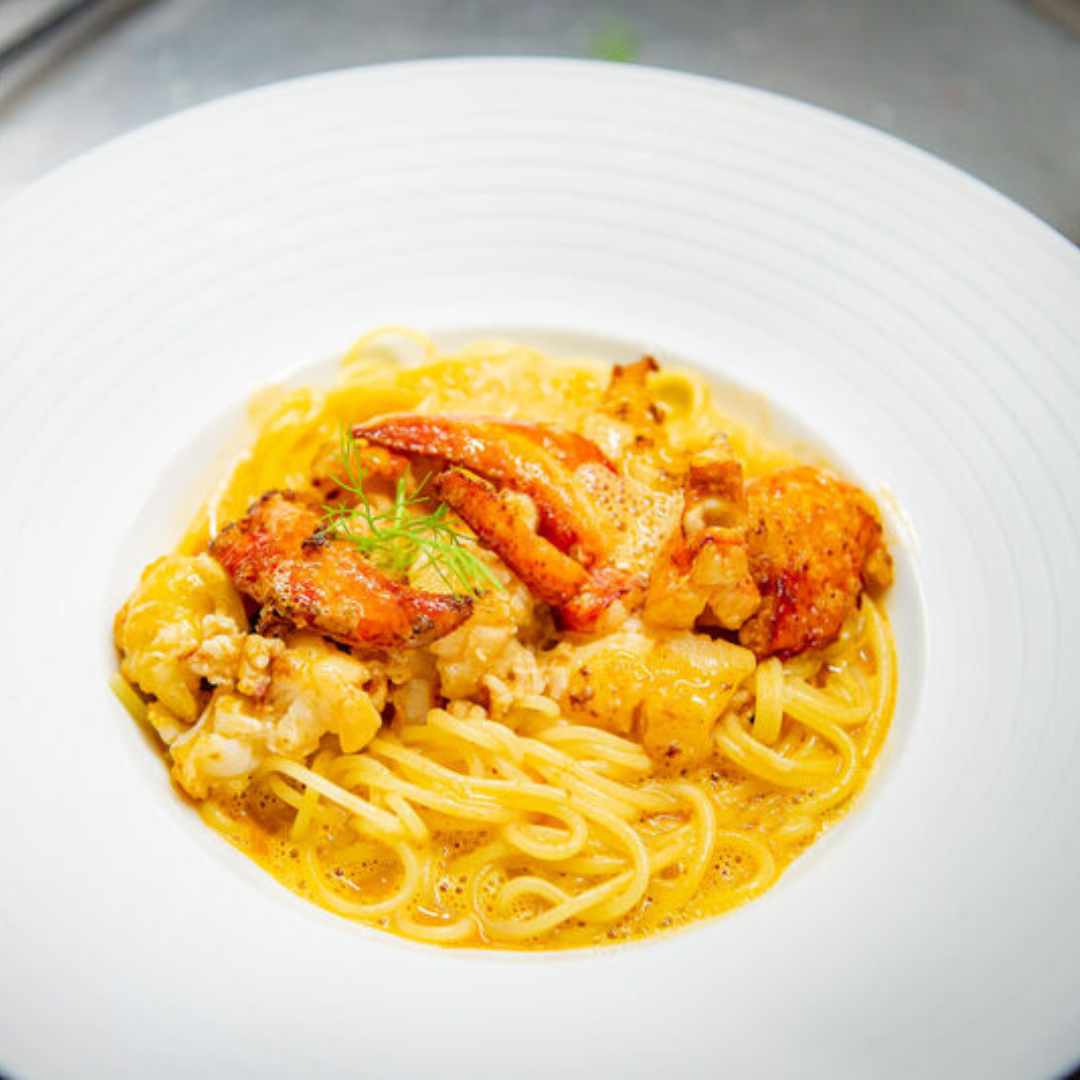 Ein Teller Meeresfrüchte-Pasta mit einer cremigen Sauce und einer Garnitur aus Dill, erinnert an die Gourmet-Geschmacksrichtungen des Großen Sylter Suppen-Sets der Sylter Manufaktur.