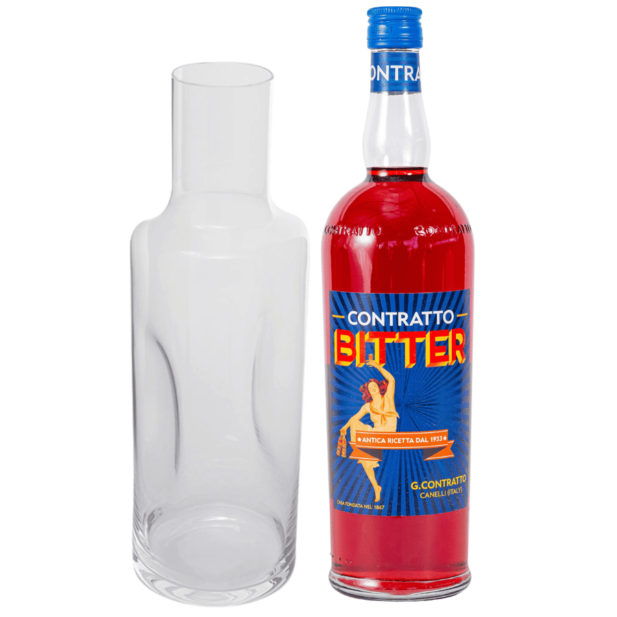 Links steht eine klare, leere Glaskaraffe, rechts steht eine Flasche Sylter Manufaktur Bitter-Aperitif mit Karaffe mit rotem Etikett und Grafiken im Vintage-Stil.