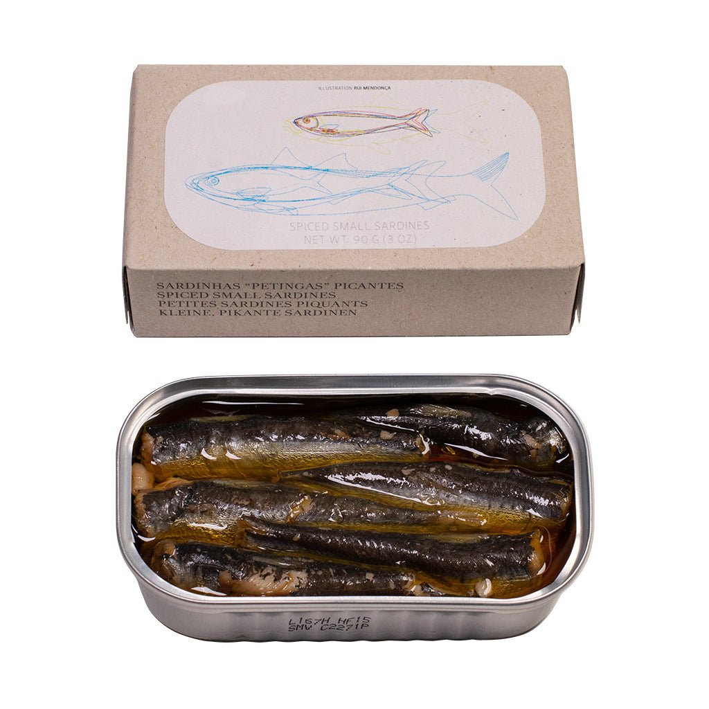 Eine Dose „Kleine, pikante Sardinen in Olivenöl“ von Jose Gourmet mit geöffnetem Deckel, durch den die Fischkonserve im Inneren sichtbar ist, und eine Verpackungsschachtel, auf deren Oberseite eine Sardine abgebildet ist.