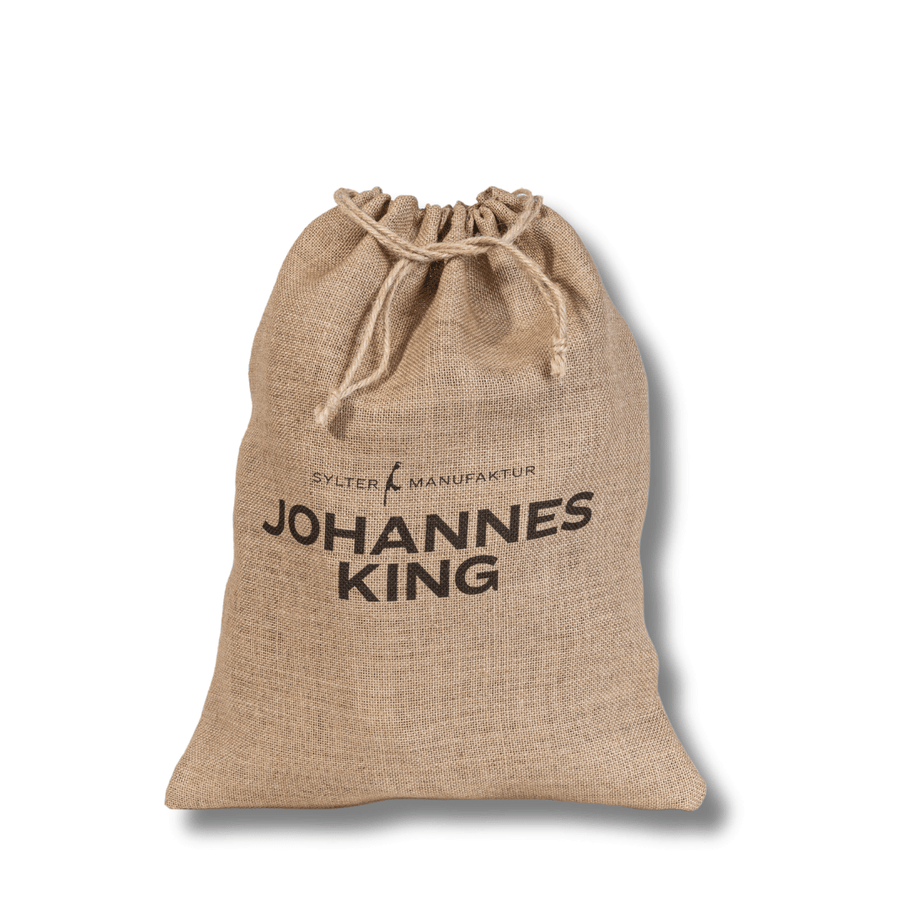 Ein Geschenkbeutel im Weihnachtsdesign der Sylter Manufaktur Johannes King, der als nachhaltige Geschenkverpackung dient und mit einem Kordelzug verschlossen wird