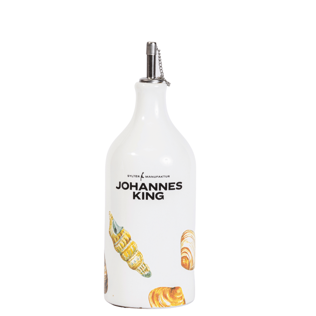 Eine weiße Keramikflasche mit einem Viani-Ausgießer aus Metall, mit der Aufschrift „Johannes King“ und verziert mit Bildern von Gebäck.