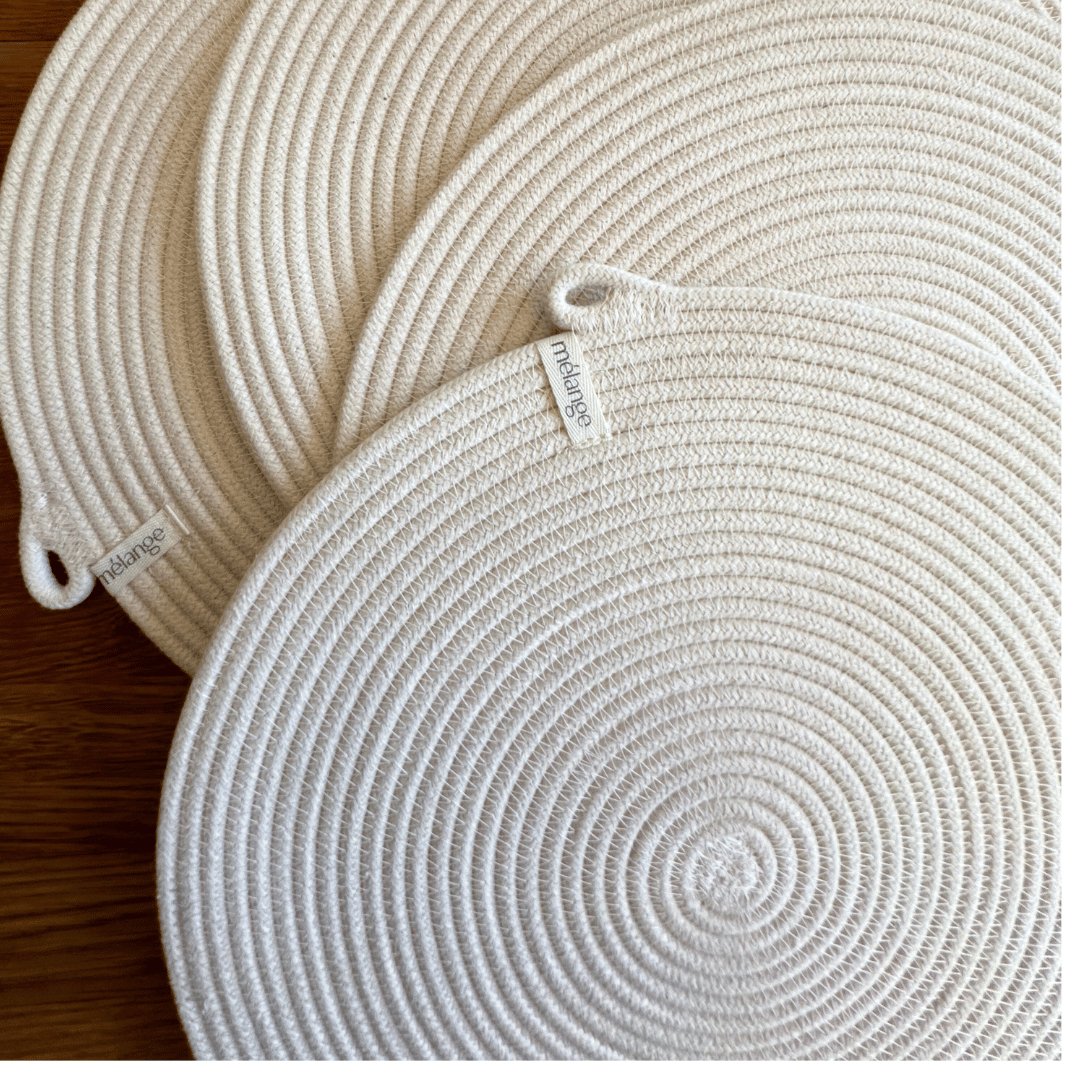 Drei runde, weiße Mia Mélange Baumwoll-Tischset (32 cm) geflochtene Stoffuntersetzer mit sichtbaren Etiketten, platziert auf einer Holzoberfläche.