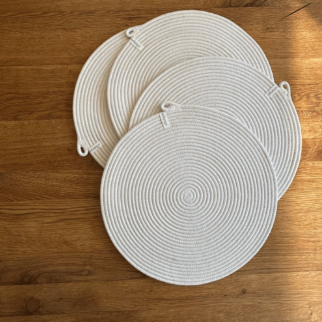 Drei runde, von Mia Mélange handgefertigte Baumwoll-Tischsets (32 cm) mit unterschiedlichen Durchmessern auf einer Holzoberfläche platziert.
